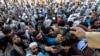 Afghan men wait to collect tokens needed to apply for Pakistan visas in Jalalabad on October 21.