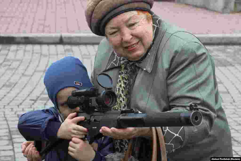 A woman assists a child with a weapon during an exhibition displaying military equipment, vehicles, and weapons of the Russian defense forces in the Black Sea port of Sevastopol, Crimea. (AFP/Denis Lovrovic)