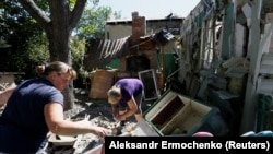 Residents remove debris outside a house that locals said was damaged during recent shelling in the rebel-controlled city of Donetsk on June 17.