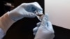 Лаборант у клініці в Каліфорнії (США) візуально розглядає заповнений флакон із досліджуваним препаратом для боротьби з коронавірусом