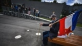 SERBIA -- An admirer wearing a protective mask holds a Yugoslavia flag as he sits on a bench in front of the late former President of communist Yugoslavia Josip Broz Tito (1892–1980) memorial complex, in Belgrade, May 25, 2020
