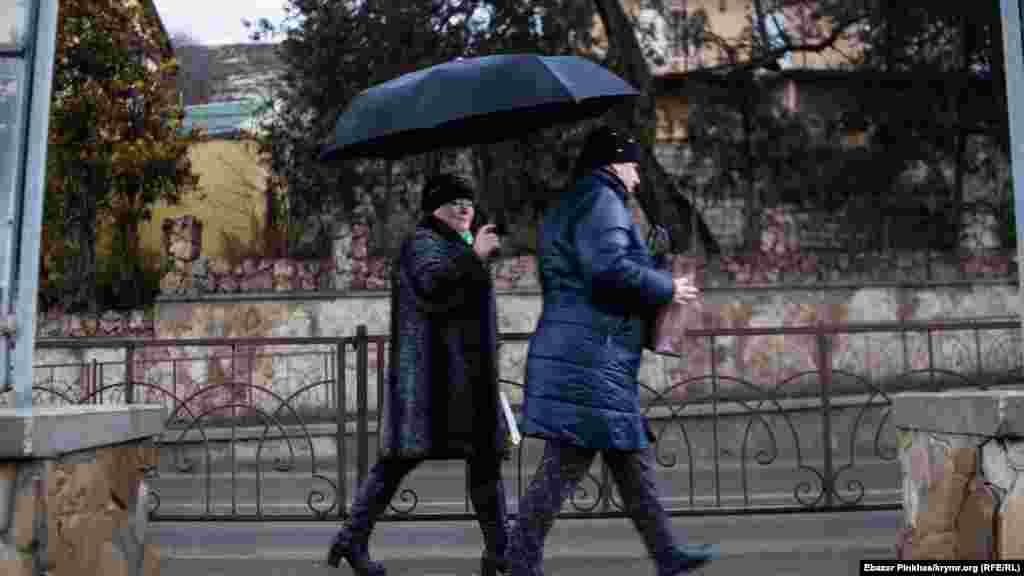 Місцеві жителі поспішають у справах, озброївшись парасольками