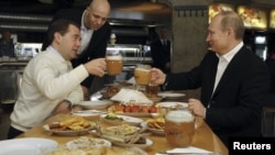 Then-President Dmitry Medvedev (left) and then-Prime Minister and President-elect Vladimir Putin toast with beers at a casual lunch meeting on May 1.