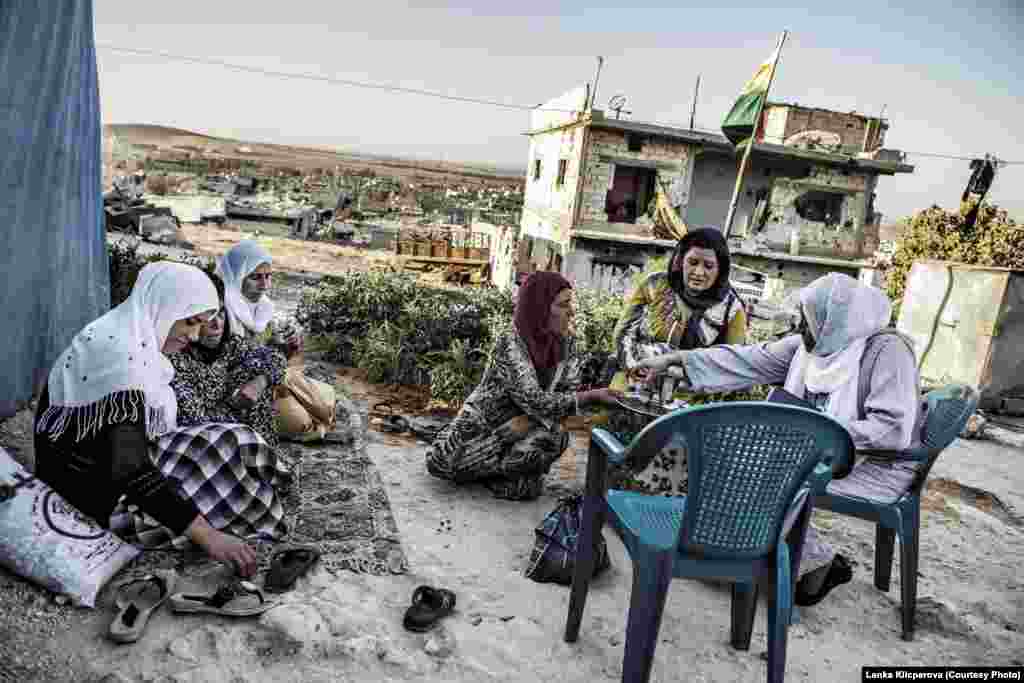 A group of women sipping tea at the top of Kobani Hill. The women live in a tent city next to their destroyed homes.