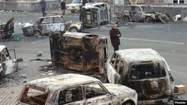 Armenia - A man walks past burned cars on a street in Yerevan where security forces clashed with opposition protesters, 2 March 2008.