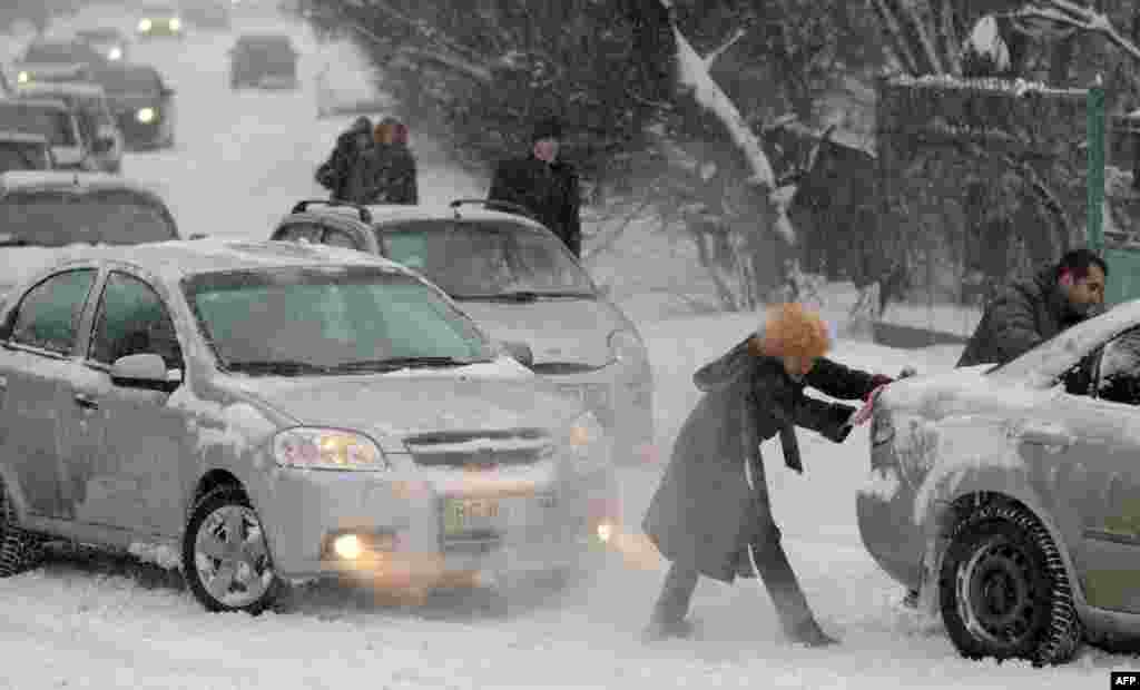 People push cars after a heavy snowfall in the Ukrainian city of Lviv. (AFP/Yuriy Dyachyshyn)