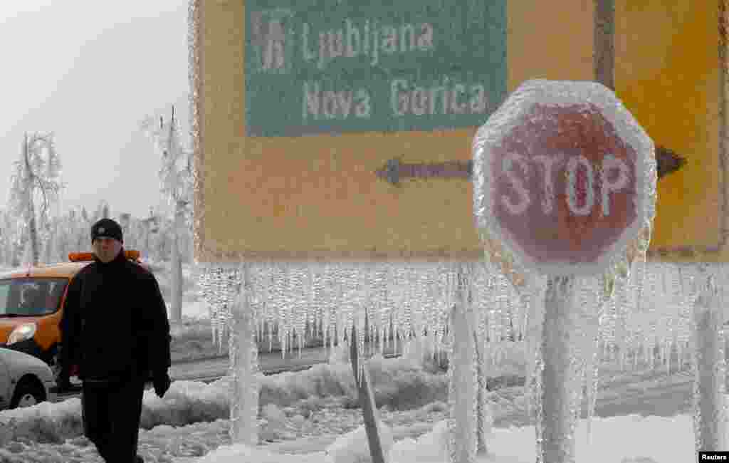 A man walks next to ice-covered road signs in Postojna, Slovenia, on February 3. (Reuters/Srdjan Zivulovic)