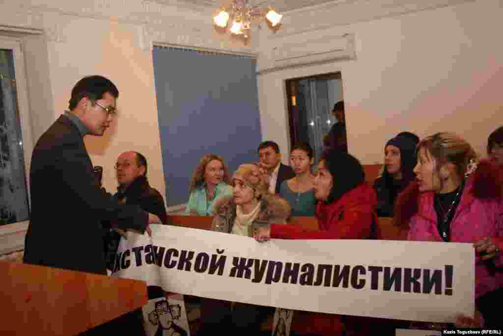 Пристав административного суда города Алматы рвёт плакат, принесенный журналистами оппозиционного издания. Алматы, 7 февраля 2013 года.