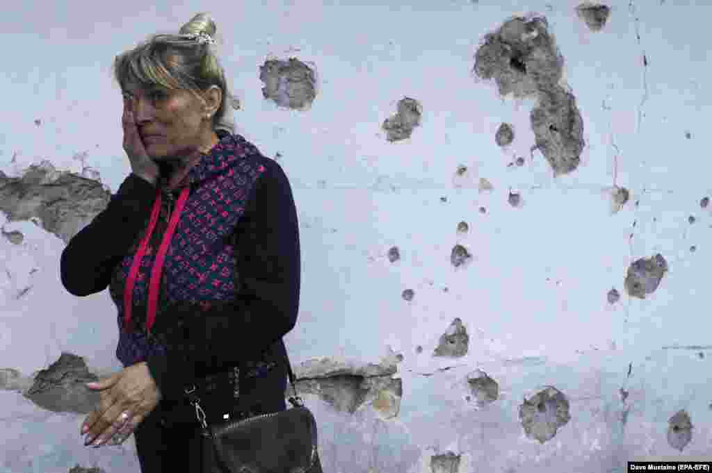 A woman weeps near the wall of her house, which was damaged by shrapnel in the separatist-controlled village of Staromihailovka in eastern Ukraine. (epa-EFE/Dave Mustaine)