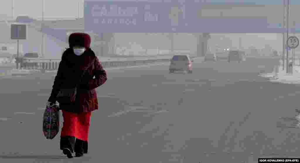 Një grua në Bishkek të Krigizisë ecën në një rrugë, ku në prapavijë shihet një pano e kandidatit për president, Sadyr Japarov. (epa-EFE/Igor Kovalenko)