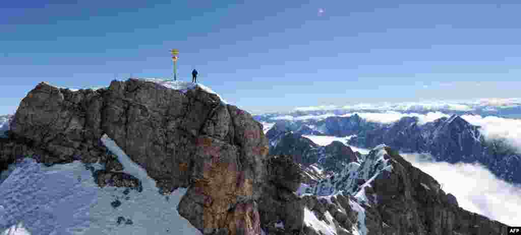 A mountain climber stands atop the peak of the Zugspitze, Germany&#39;s tallest mountain, overlooking the Bavarian Alps. (AFP/Tobias Hase)