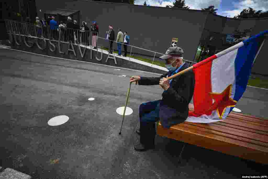 An admirer holds a Yugoslav flag as he sits on a bench in front of the memorial complex dedicated to the late former president of Yugoslavia, Josip Broz Tito, in Belgrade. Groups of people flocked to Tito&#39;s memorial to mark his 128th birthday. (AFP/Andrej Isakovic)