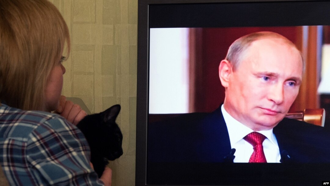 A woman looks at Russian President Vladimir Putin on screen as she watches the documentary Crimea: Path To The Homeland on March 15. 
