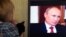 A woman looks at Russian President Vladimir Putin on screen as she watches the documentary Crimea: Path To The Homeland on March 15. 