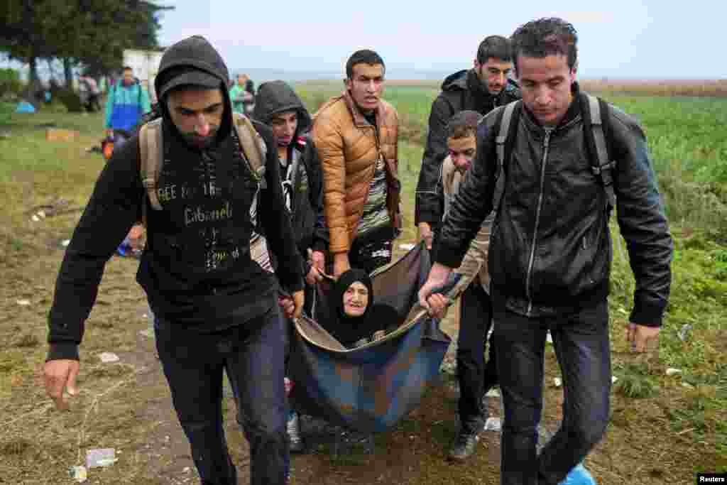 Migrants carry an elderly woman as they walk in a field after crossing the border with Serbia, near Tovarnik, Croatia. (Reuters/Marko Djurica)