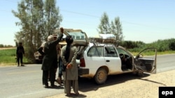 Members of the Afghan security forces check a vehicle on a road near Greshk district of Helmand Province on June 21.