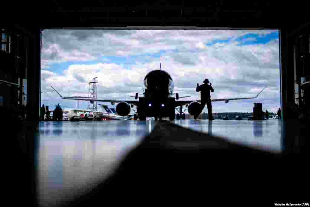 An aircraft mechanic assists to park the Embraer-175 airplane inside a hangar at the airport outside Minsk. (AFP/Maksim Malinovsky)