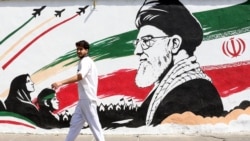 A man walks past a mural depicting late Iranian supreme leader Ayatollah Ali Khamenei in Tehran on July 24. 
