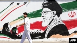 A man walks past a mural depicting late Iranian supreme leader Ayatollah Ali Khamenei in Tehran on July 24. 