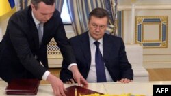 Виктор Янукович подписывает соглашение, которое он не хотел бы подписывать