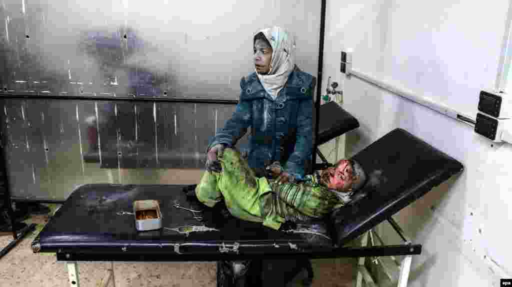 A Syrian woman sits with an injured child at a hospital following a reported strike by government forces in the rebel-held district of Barzah, on the northeastern outskirts of the capital Damascus on February 20. (epa/Sarieh Abu Zaid)