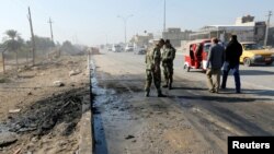 Iraqi security forces stand at the site of a car-bomb attack in the Al-Obaidi neighborhood of Baghdad on January 5.