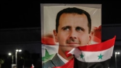 (FILES) Syrians wave national flags and carry a large portrait of ousted president as they celebrate in the streets of the capital Damascus, a day after an election which gave Bashar al-Assad a fourth term, on May 27, 2021.