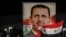 (FILES) Syrians wave national flags and carry a large portrait of ousted president as they celebrate in the streets of the capital Damascus, a day after an election which gave Bashar al-Assad a fourth term, on May 27, 2021.