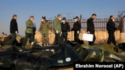 مأموران امنیتی جمهوری اسلامی بر سر بقایای هواپیمای مسافری سرنگون‌شده توسط سپاه پاسداران