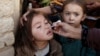 A girl receives polio vaccine drops from a vaccination worker outside her family home in Quetta, Pakistan, in January.
