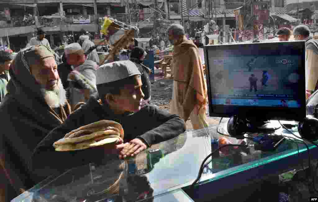 Afghan refugees watch a live broadcast of the Cricket World Cup match between Afghanistan and Bangladesh at a market in Peshawar, Pakistan on February 18, 2015. (AFP/A Majeed) 