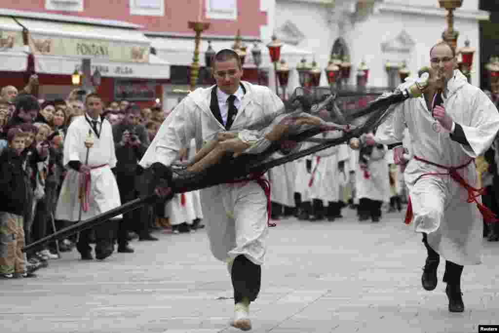 Muškarac trči sa krstom tokom procesije &quot;Za križem&quot; u Jelsi, na hrvatskom otoku Hvaru, 18. april (Reuters/Antonio Bronić)