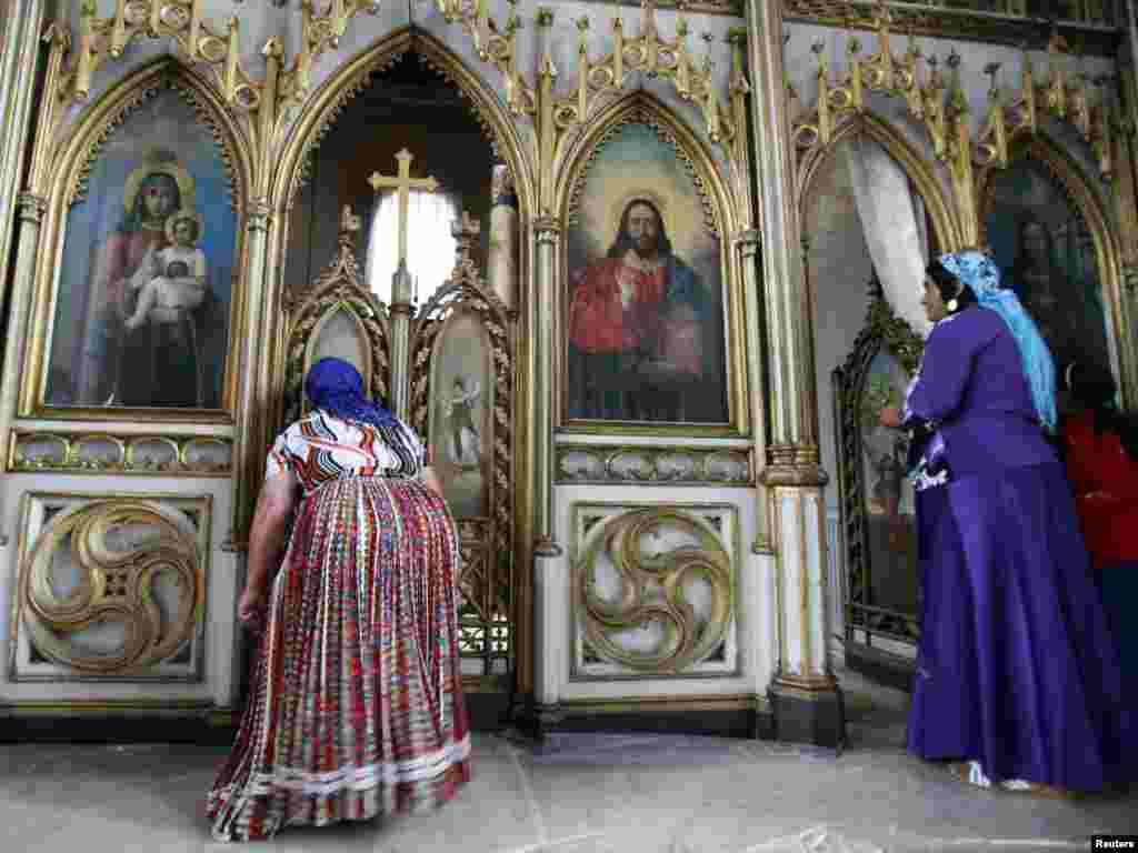 Two Romany women pray inside an Orthodox church during the gathering of the Romany minority in Costesti, Romania, on September 8. (Photo by Radu Sigheti for Reuters)