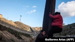 Мигранты из центральноамериканских стран пытаюсь преодолеть пограничное заграждение рядом с мексиканским городом Тихуана