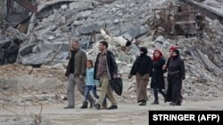 Цивільні люди йдуть зруйнованими вулицями Харасти, раніше утримуваного повстанцями міста в Східній Гуті, Сирія, 30 березня 2018 року