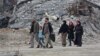 Civilians walk along a destroyed street in the former rebel-held town of Harasta in eastern Ghouta.