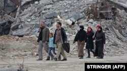 Civilians walk along a destroyed street in the former rebel-held town of Harasta in eastern Ghouta.