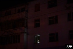 Un bărbat, ținând o lanternă la geamul apartamentului său din Varnița, sat din dreapta Nistrului conectat la rețeaua electrică transnistreană, în timpul deconectărilor programate de curent electric, pe 17 ianuarie 2025