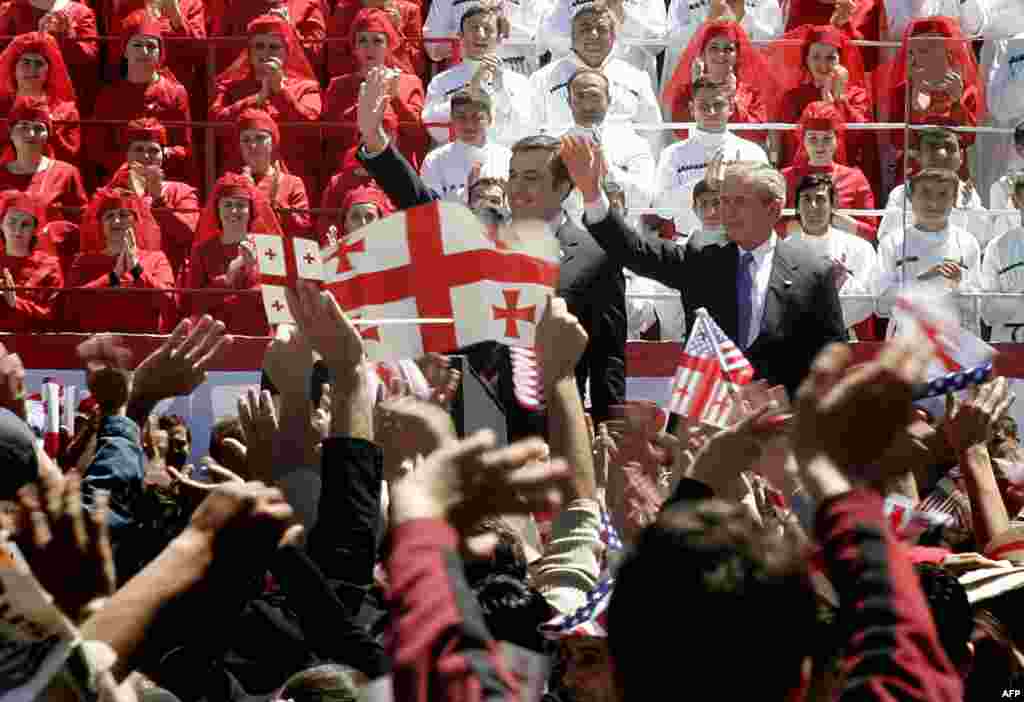 President Mikheil Saakashvili (left) and U.S. President George W. Bush (right) wave to the crowd in Tbilisi on May 10, 2005. The peaceful resolution of conflicts is "essential" for Georgia to be integrated into the West, Bush told the tens of thousands of people in the crowd.