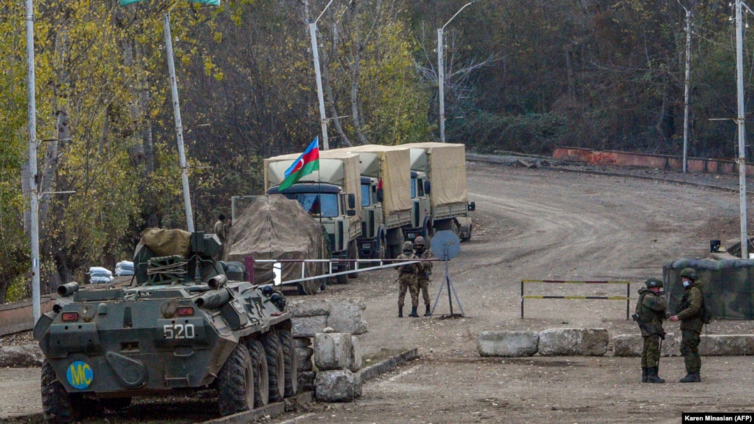 NAGORNO-KARABAKH -- Russian APC and soldiers of the peacekeeping force (L) patrol in front of an Azerbaijan's army checkpoint near the demarcation line outside the town of Shushi (Susa), November 26, 2020