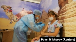 Сауда орталығындағы екпе пунктінде вакцина салдырып отырған әйел. Алматы, 23 маусым, 2021 жыл.