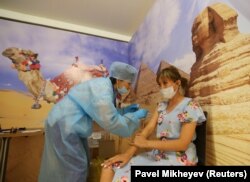 Женщина получает дозу вакцины «Спутник V» во временном пункте вакцинации, созданном в бывшей студии TikTok в торговом центре MEGA Park в Алматы, Казахстан, 23 июня 2021 года