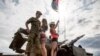 A Russian soldier poses with young women on top of a Tunguska anti-aircraft system during the Nashestvie rock festival in Russia&#39;s Tver region, near Moscow.