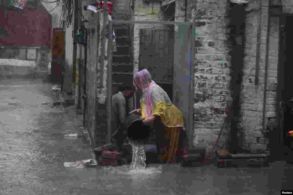 A man helps his wife remove water from their home in Lahore.
