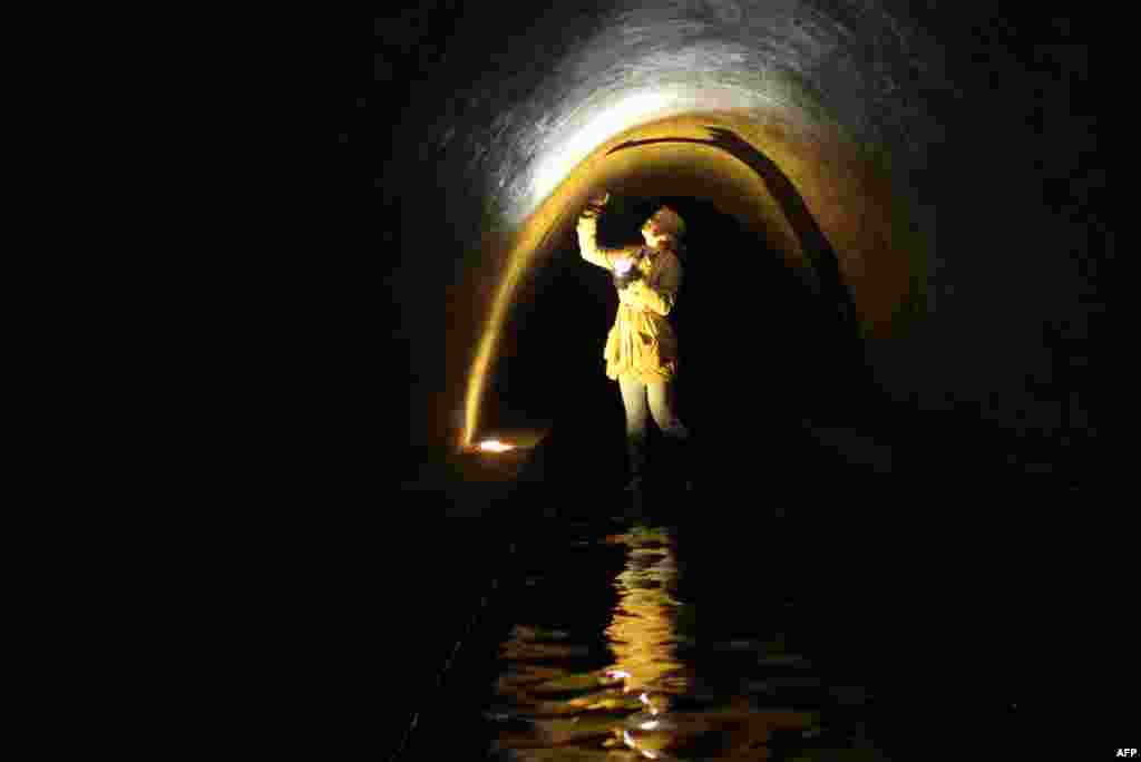 A young woman stands knee deep in the Nemiga River flowing through a large brick sewer under the Belarusian capital, Minsk, on April 25. (AFP/Sergei Gapon)