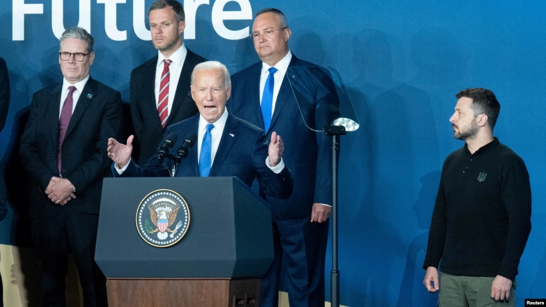 U.S. President Joe Biden speaks at the conclusion of the NATO summit in Washington on July 11, as Ukrainian President Volodymyr Zelenskiy (right) and other other foreign leaders look on.