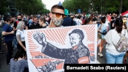 Оппозиционный демонстрант в Будапеште держит плакат с изображением Виктора Орбана как китайского коммунистического вождя Мао Цзэдуна