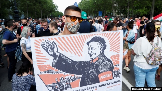 Оппозиционный демонстрант в Будапеште держит плакат с изображением Виктора Орбана как китайского коммунистического вождя Мао Цзэдуна