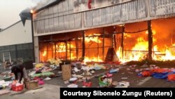 Lángokban áll egy bevásárlóközpont a tüntetéseket követő fosztogatás után a dél-afrikai Pietermaritzburgban 2021. július 13-án