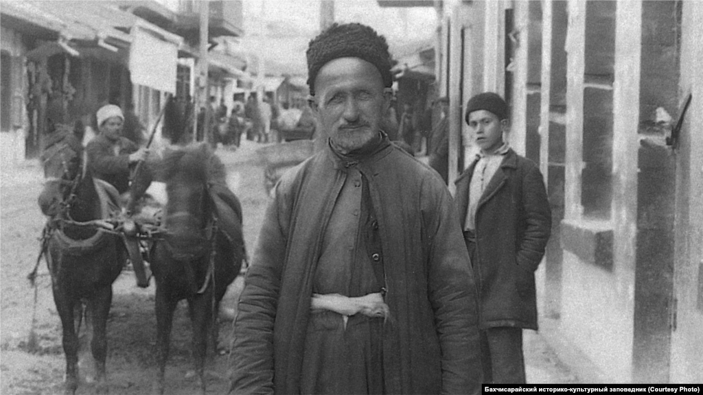 Bakhchysaray, 1920s. Men covered their heads with a low cap made of sheep leather, a skullcap, or fez hat. A shirt with wide sleeves was tucked into wide cloth harem pants and was belted with a wide sash. A short vest with buttons was put on top of the shirt, and a long caftan on top of it.